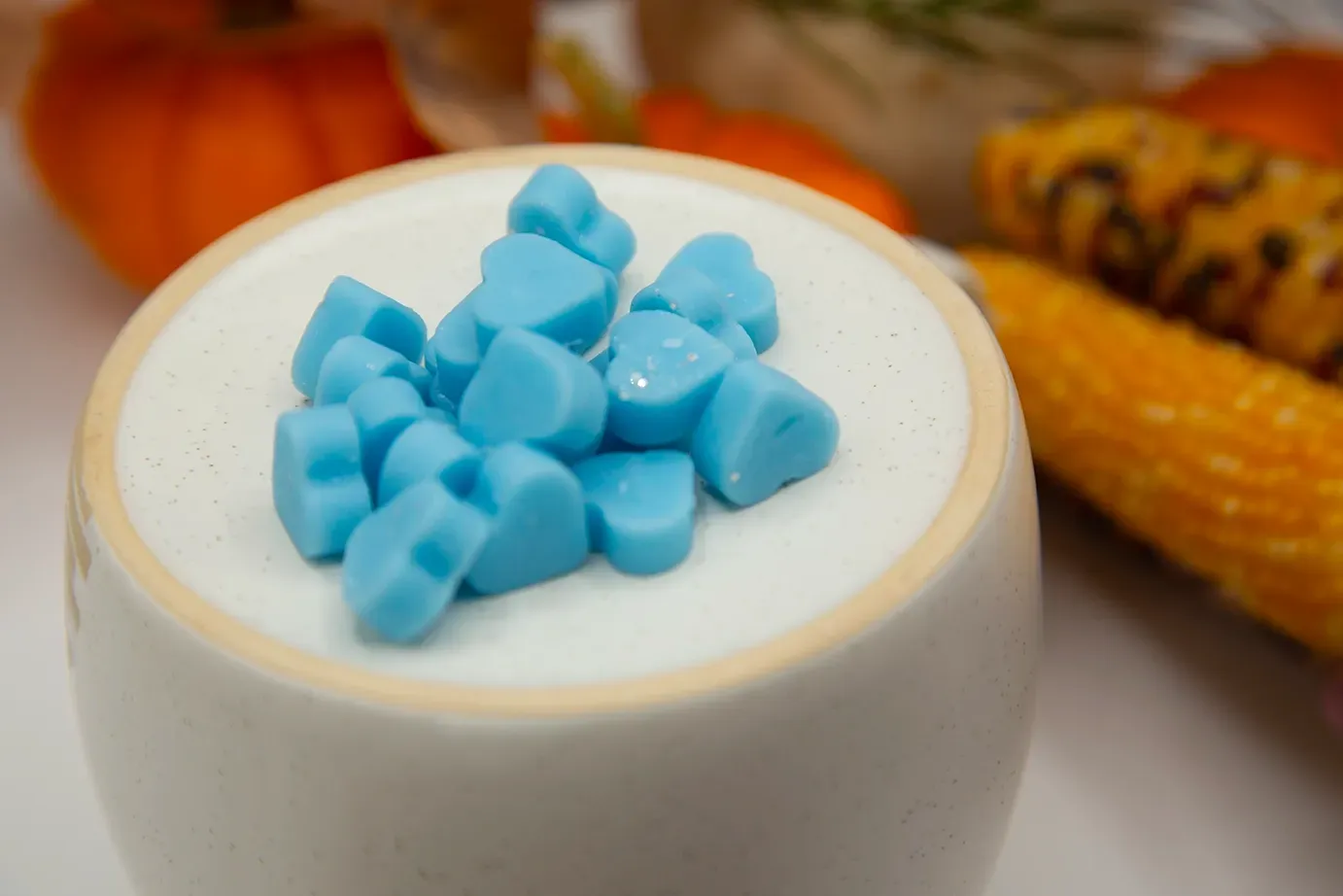 A white bowl filled with blue hearts on top of a white surface.