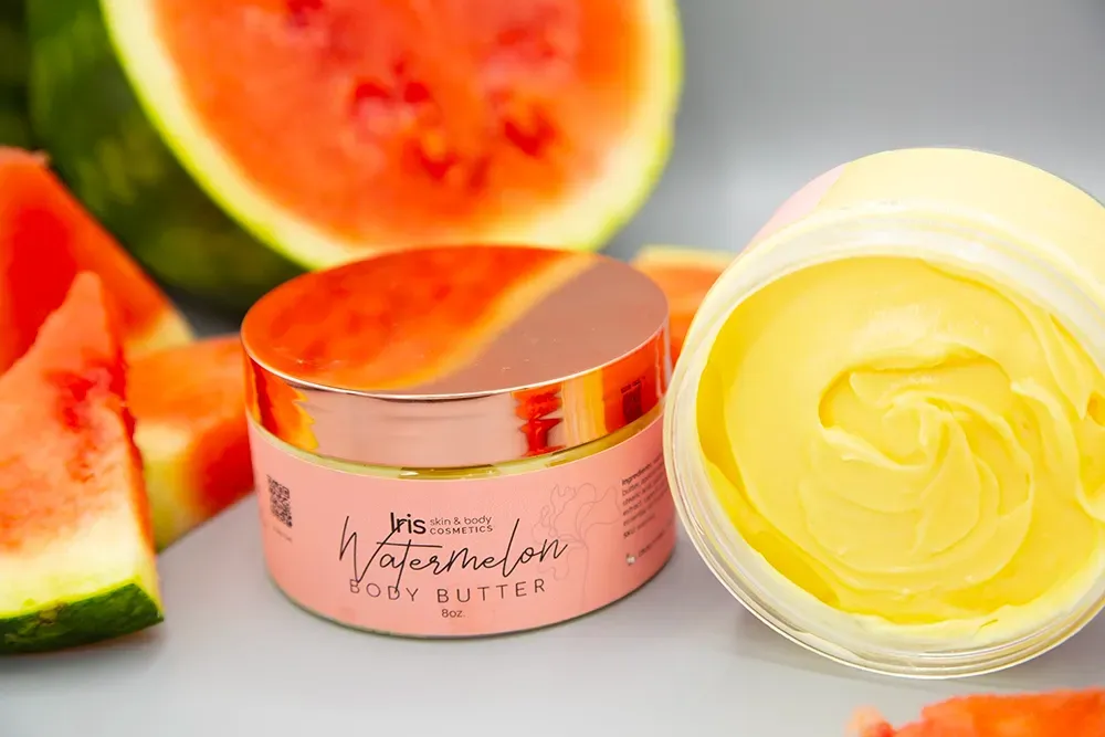 A jar of watermelon body butter is sitting on a table next to watermelon slices.