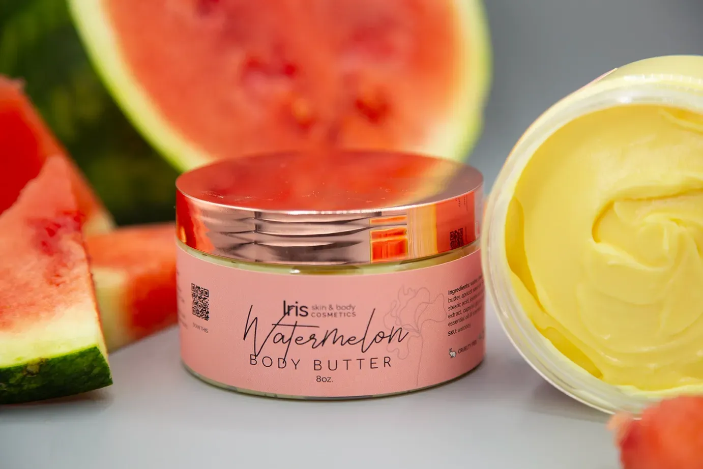 A jar of watermelon body butter is sitting on a table next to watermelon slices.