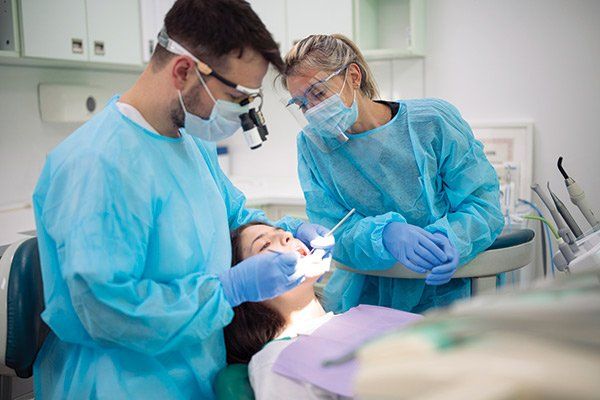 Dentist Examining Patient Mouth — Albuquerque, NM — New Mexico Endodontic Specialists Dentist Examining Patient Mouth — Albuquerque, NM — New Mexico Endodontic Specialists