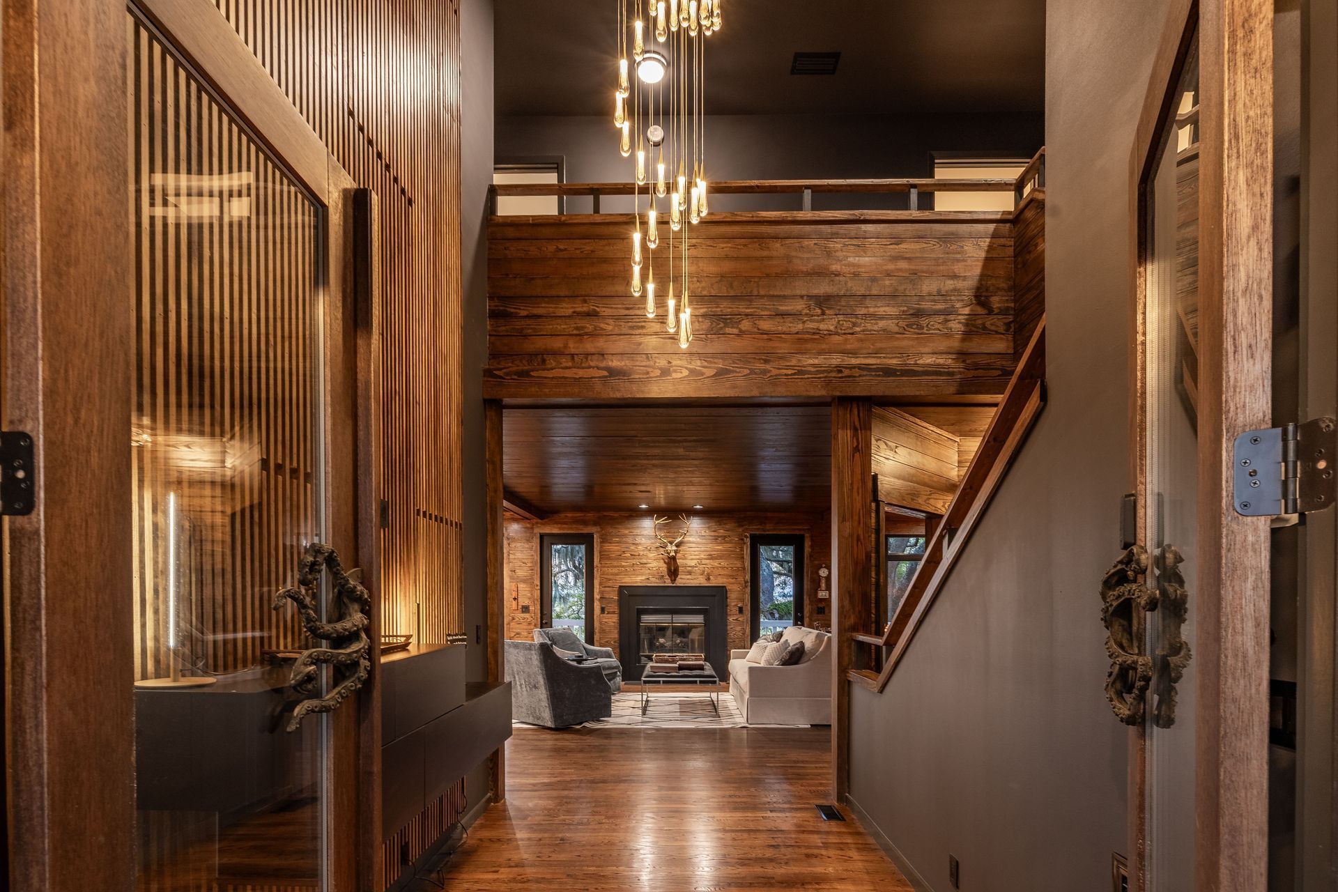 Interior hallway with wooden details, leading to a living room with a fireplace.