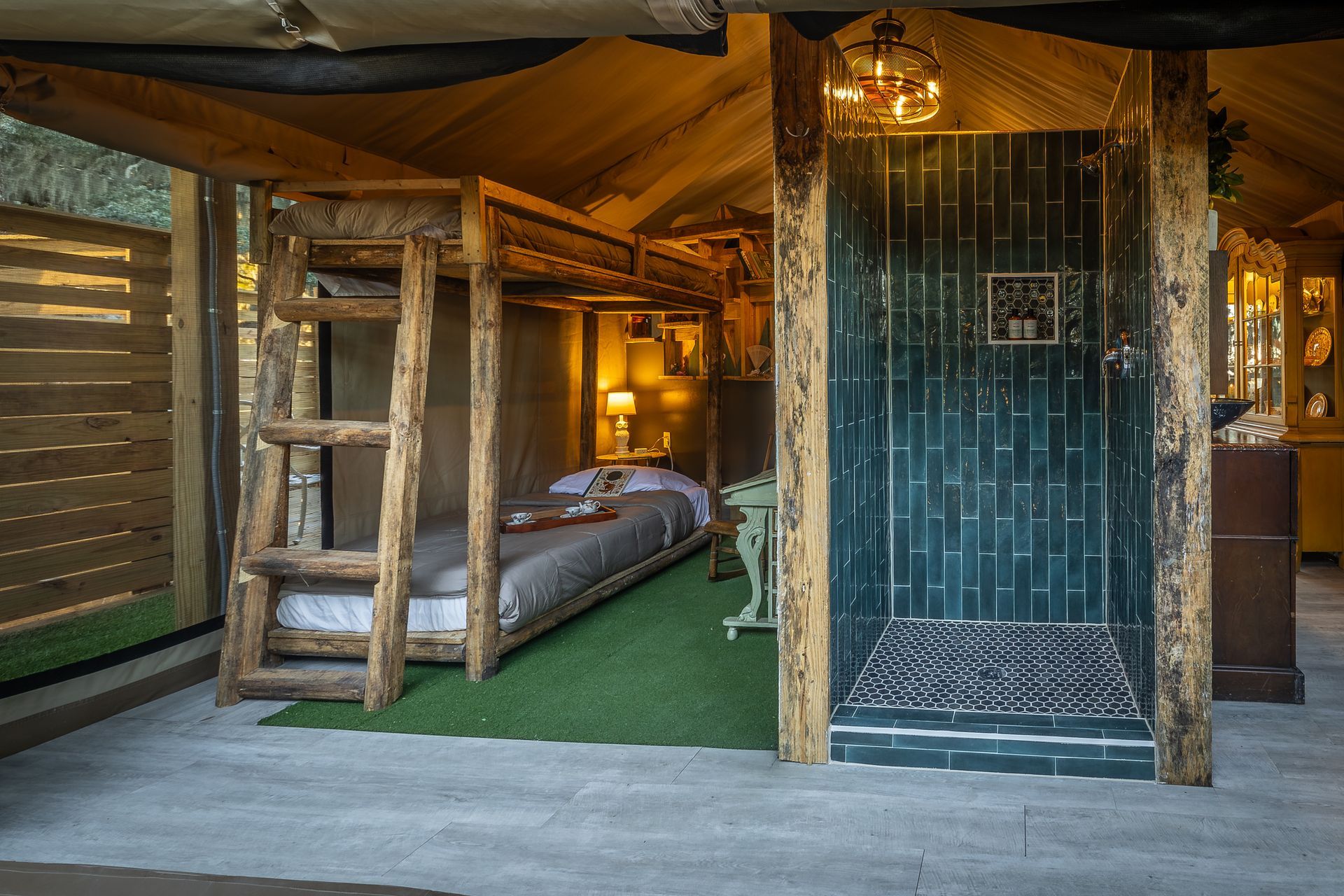 Wooden bunk beds and a shower in a rustic cabin with a green rug.