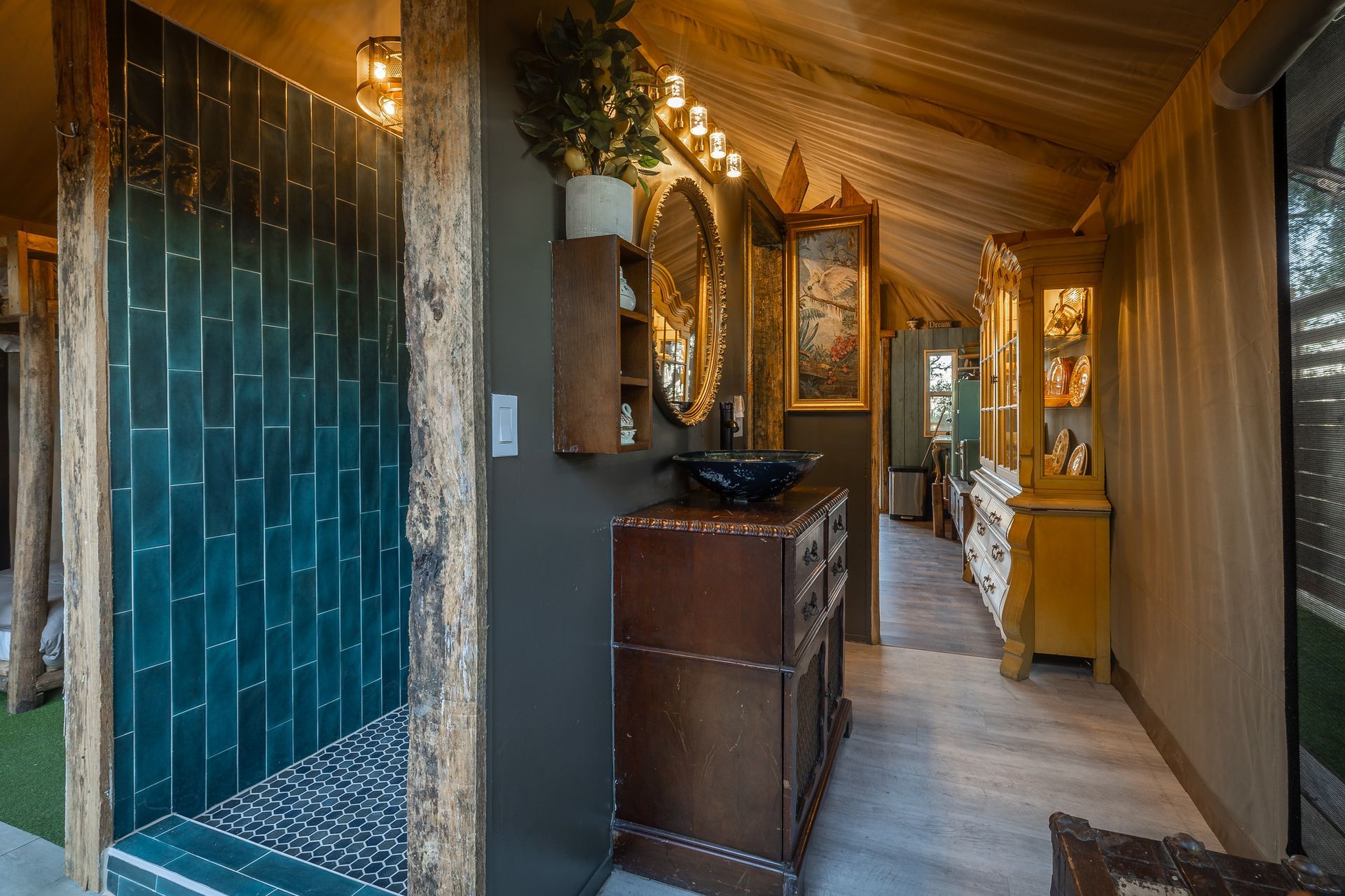 Luxurious bathroom with teal tile shower, ornate mirror, and antique furniture.