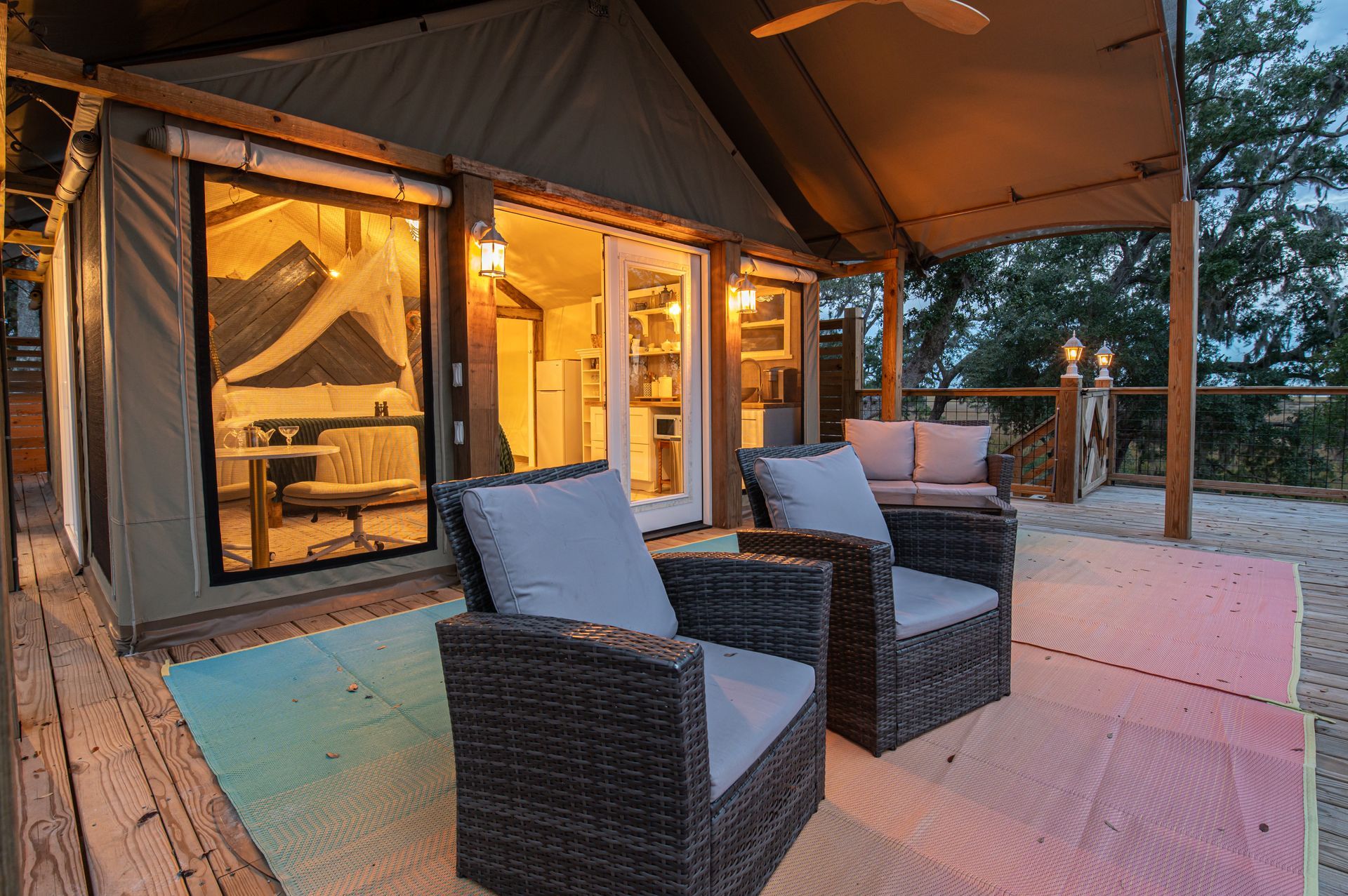 Outdoor patio with two wicker chairs, a sofa, and sliding glass doors to a glamping tent.