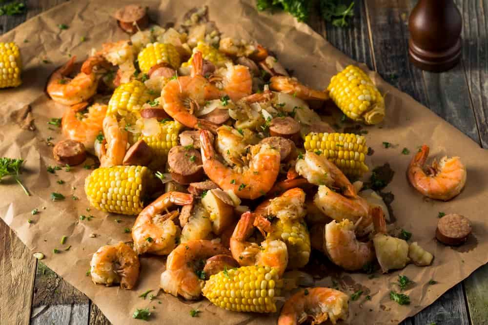 Shrimp boil with corn, sausage, and potatoes on parchment paper.