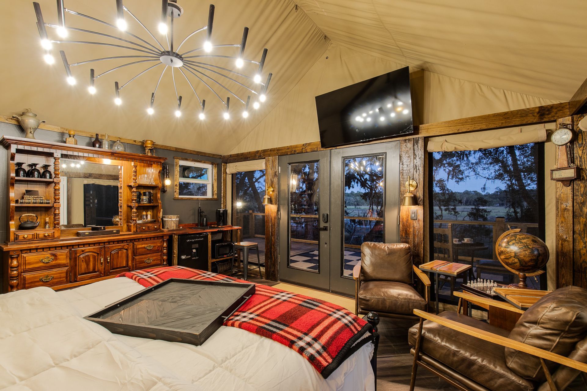 Luxurious glamping bedroom with a bed, vanity, and seating area.