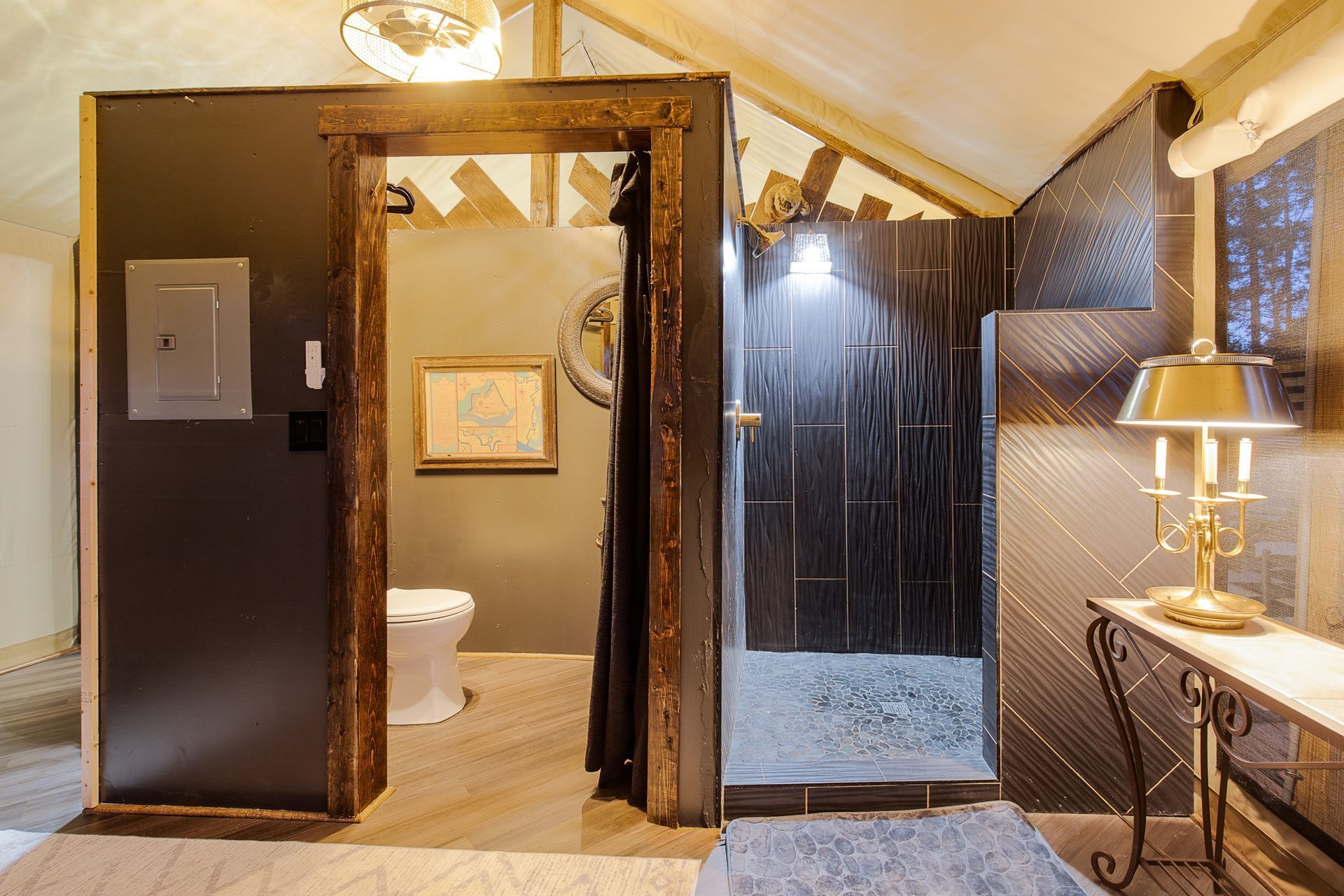 Rustic bathroom with dark walls, wooden trim, and a small vanity with lamp.