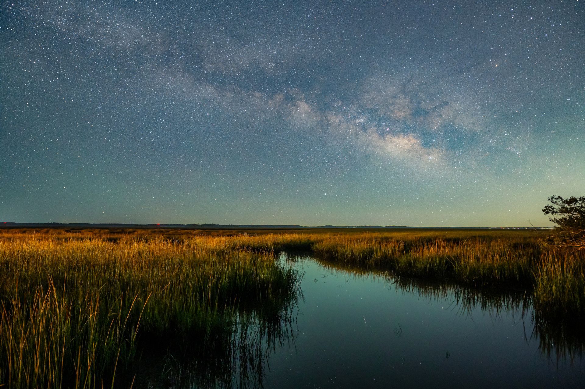 Milky Way over a marsh at night; water reflects stars.