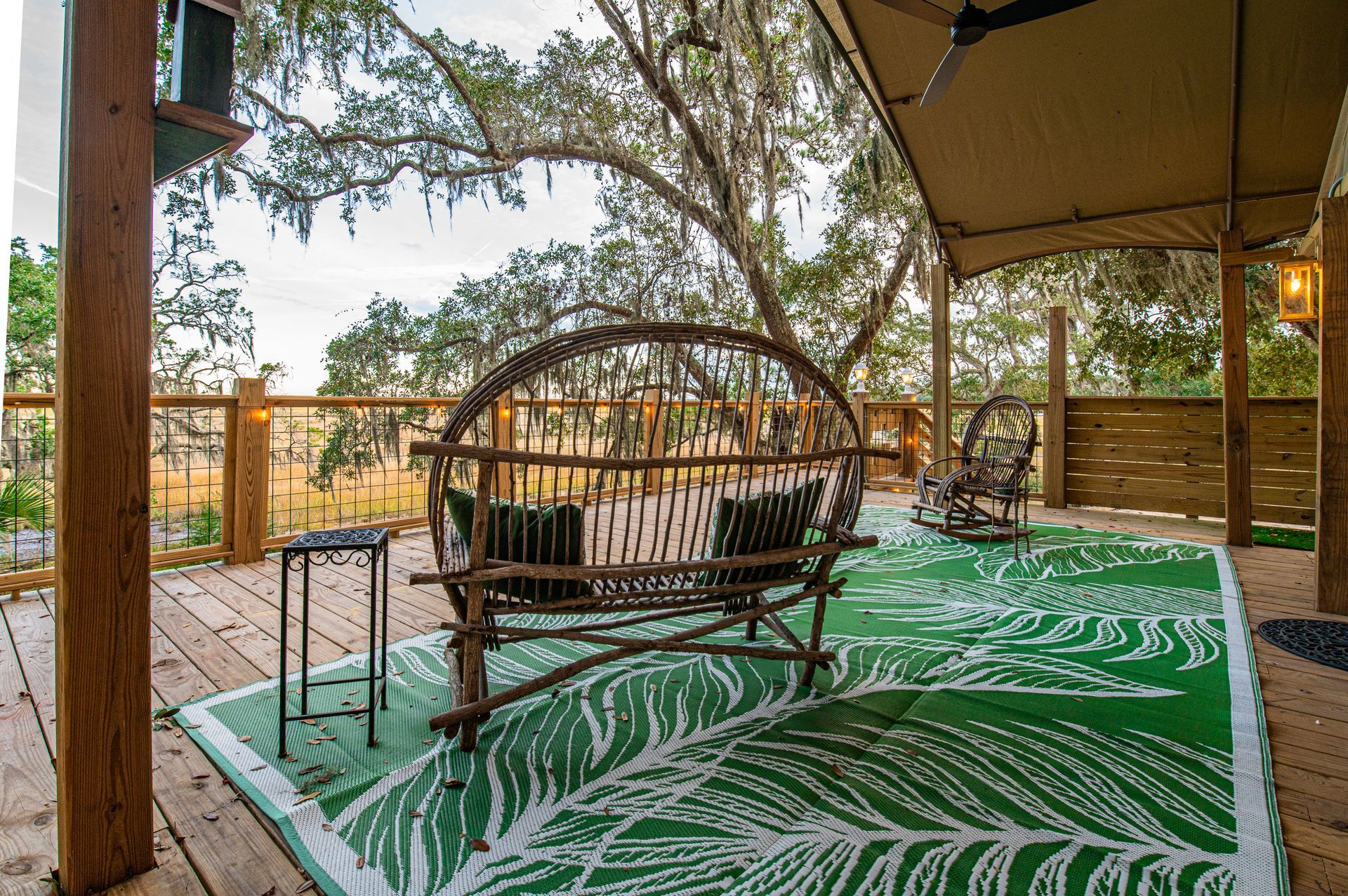 Outdoor patio with a swing, rocking chair, and green leaf-patterned rug.