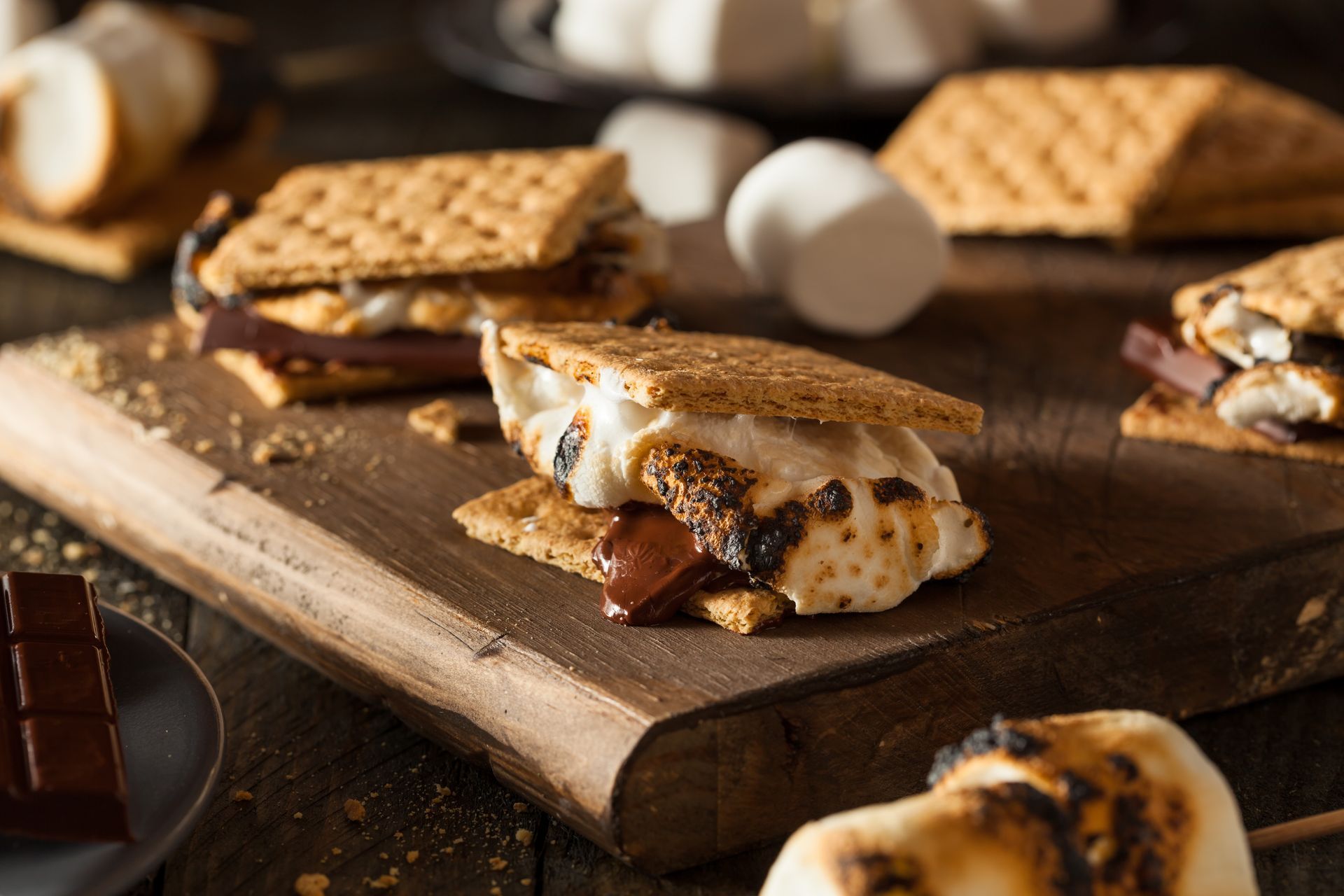 S'mores on a wooden board: toasted marshmallow and chocolate between graham crackers.