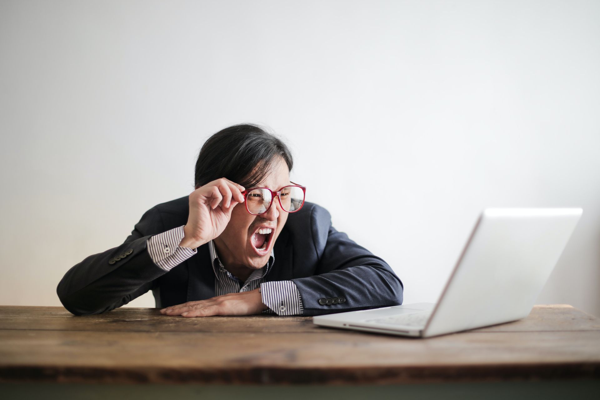 A man staring at his laptop with the look of shock on his face.