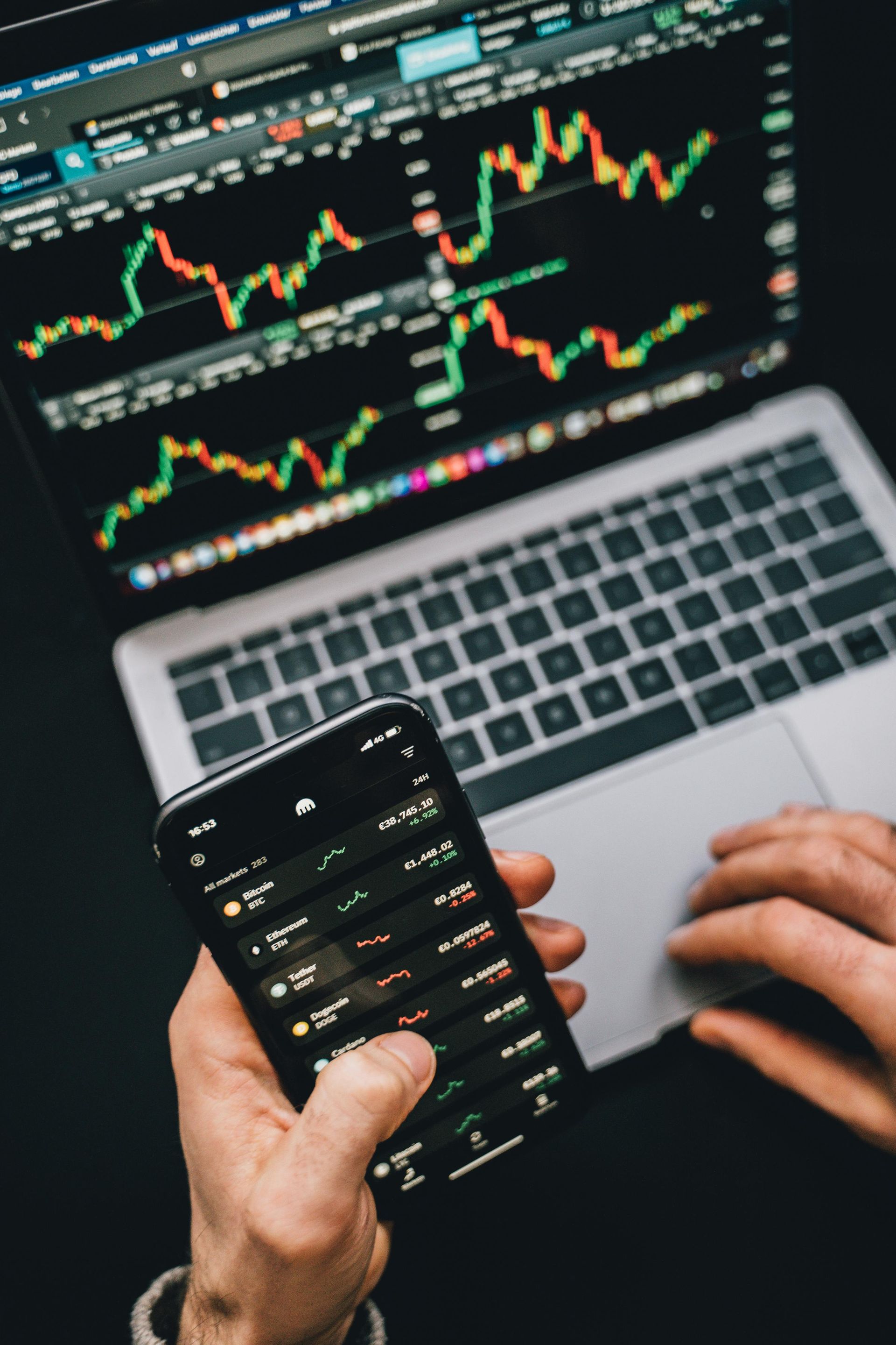 Image of a laptop and cellphone with stock charts and prices.