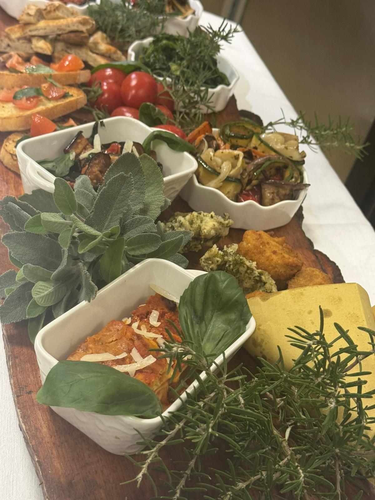 Vari piatti al forno ed erbe aromatiche disposti su un tavolo di legno a buffet