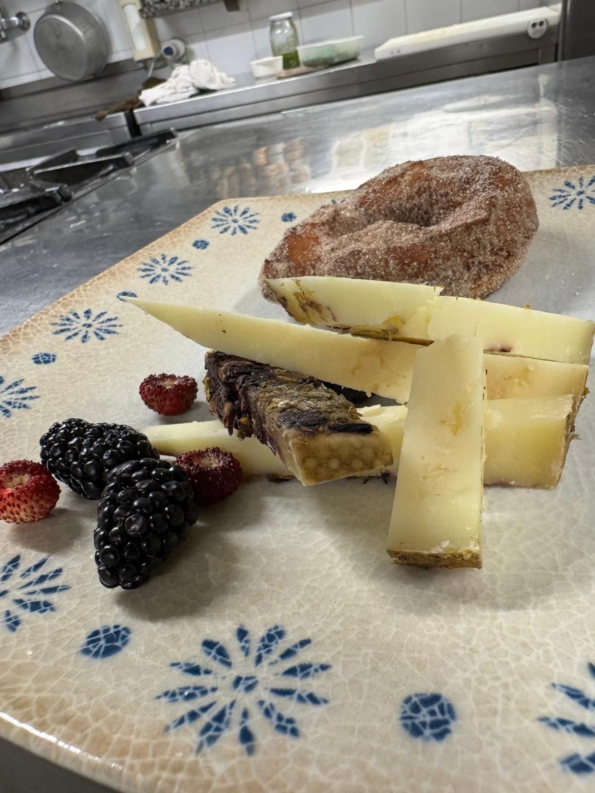 Spicchi di formaggio con frutti di bosco e pasta sfoglia cosparsa di zucchero su un piatto decorato.