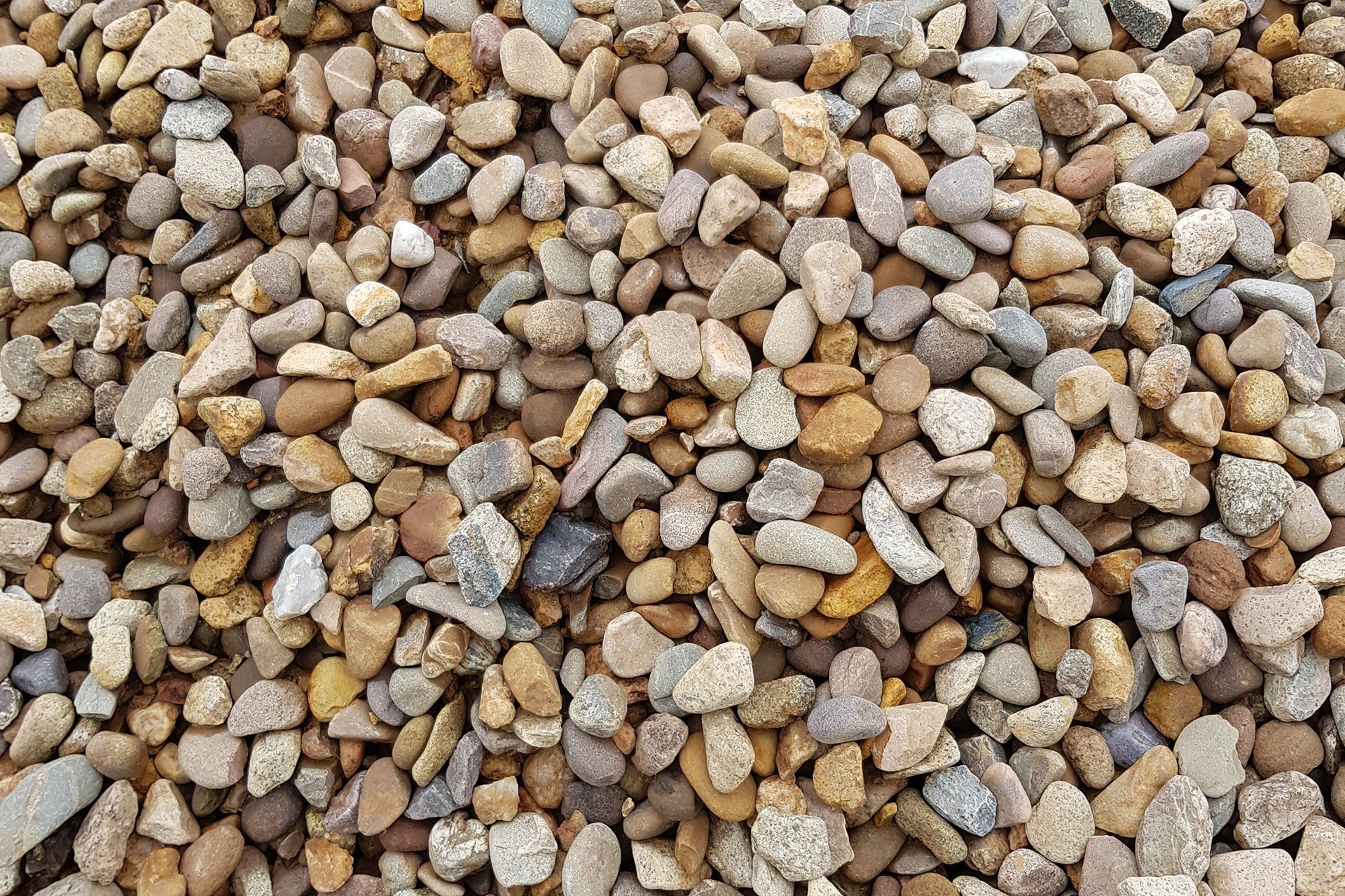 Pile of tan, brown, and gray landscaping gravel.
