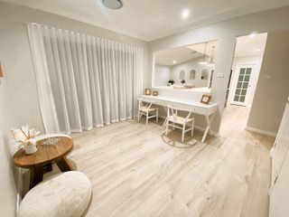 A living room with a desk , chairs , a table and curtains — Plantation Shutters in Singleton, NSW