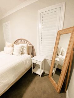 A bedroom with a bed , nightstand , mirror and shutters — Plantation Shutters in Singleton, NSW