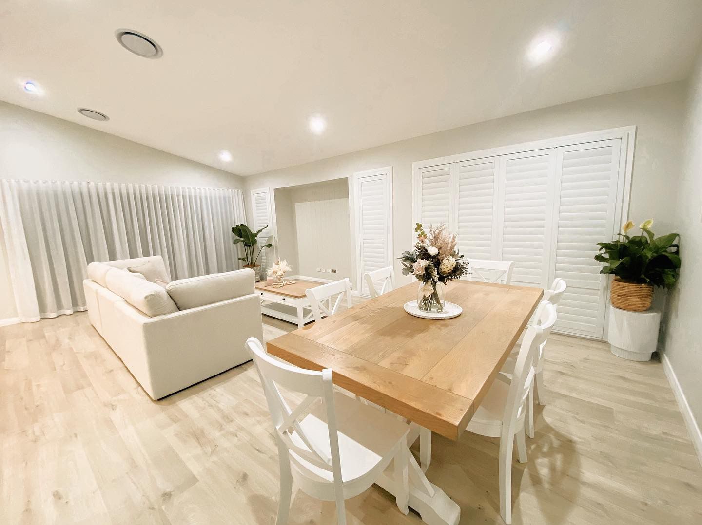 A living room with a dining table and chairs and a couch — Plantation Shutters in Singleton, NSW