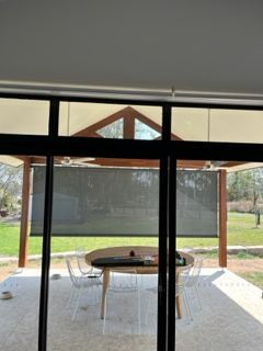 A patio with a table and chairs is visible through a sliding glass door — Plantation Shutters in Singleton, NSW