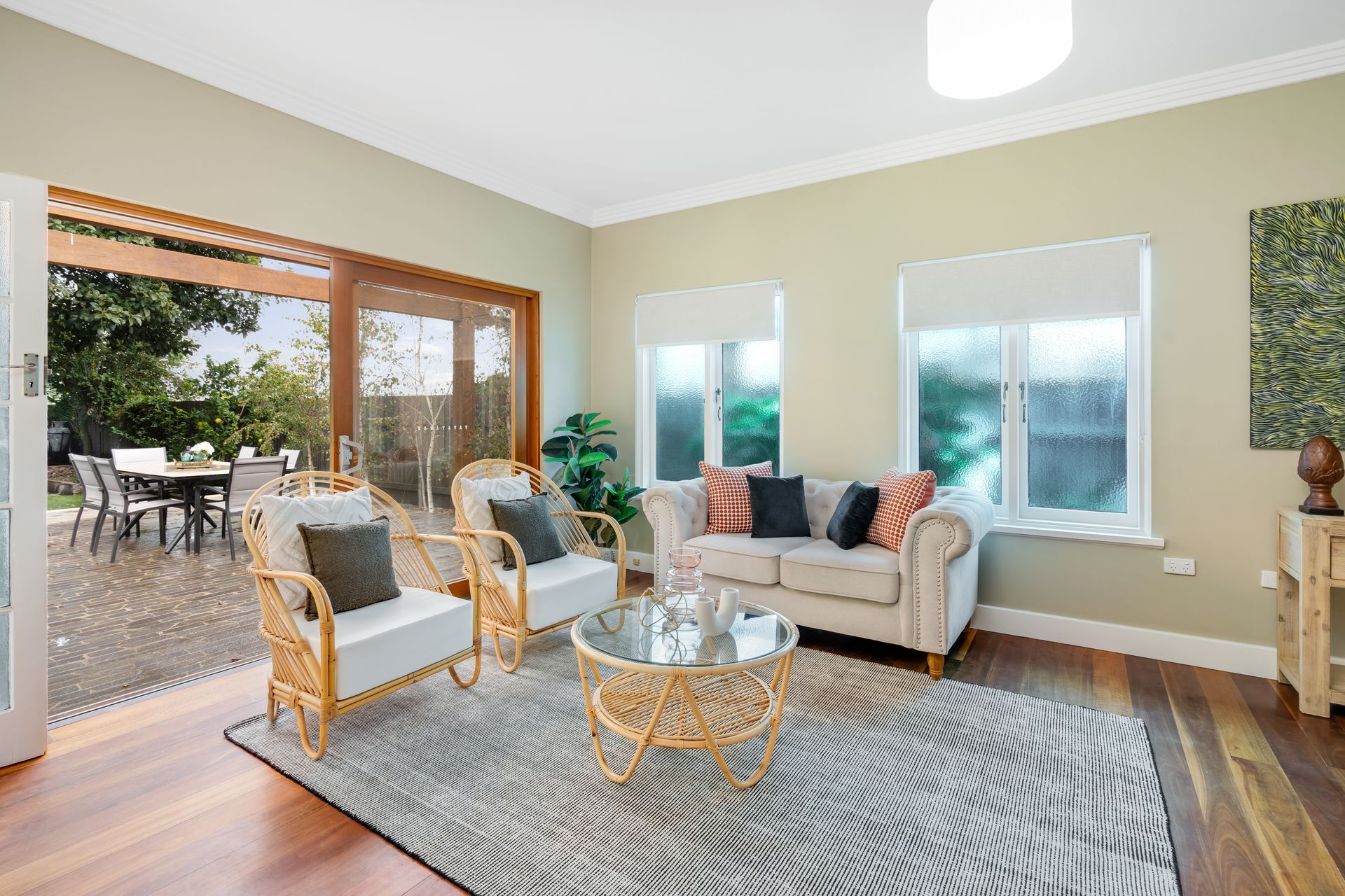 A living room with a couch , chairs , a table and a rug — Plantation Shutters in Singleton, NSW
