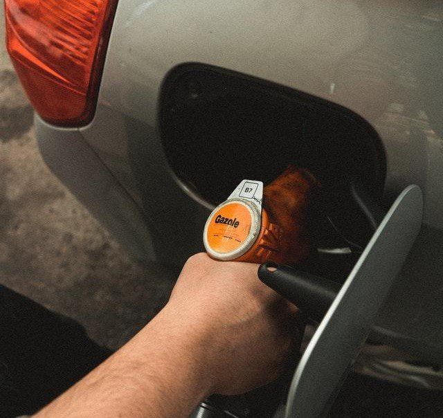 A person is pumping gas into a silver car