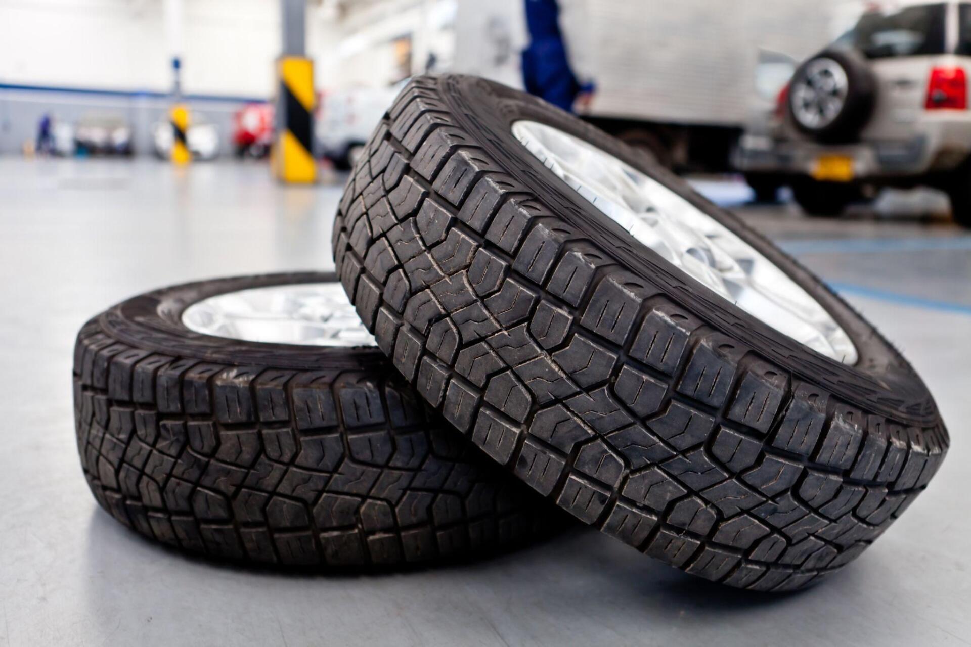 Two tires are stacked on top of each other in a garage.