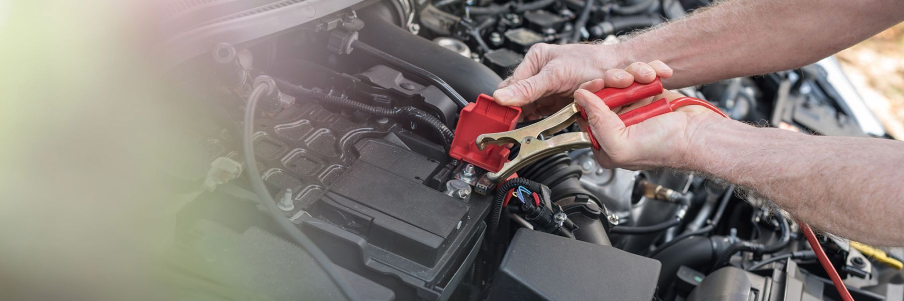 Mechanic using red pliers to work on car engine parts