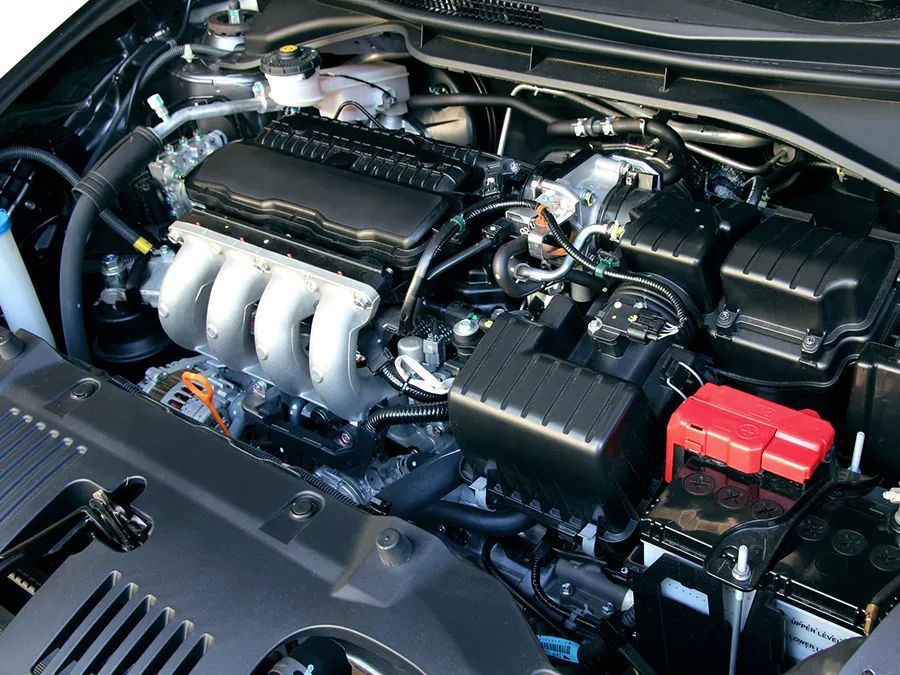 Car engine bay with engine, air filter, and battery.