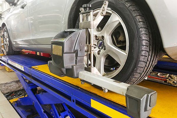 A car is being aligned on a lift in a garage.