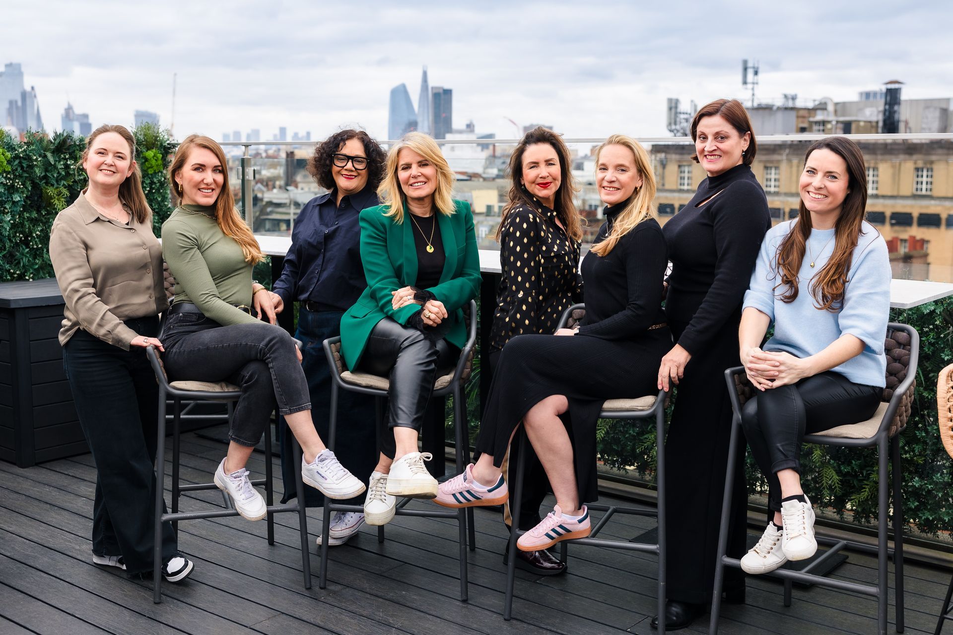 a group of women are sitting on stools on a rooftop .
