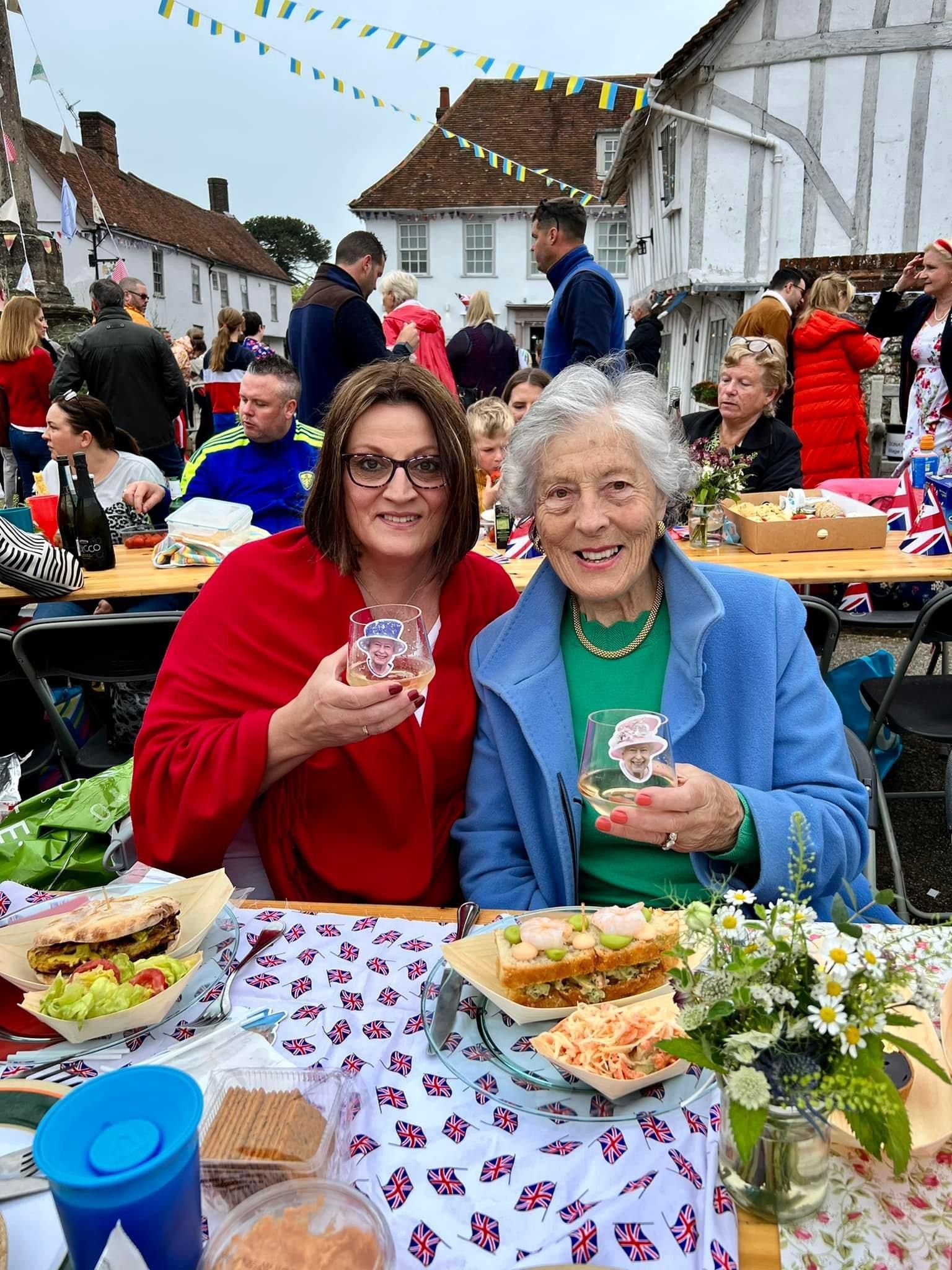 two women are sitting at a table with sandwiches and drinks .