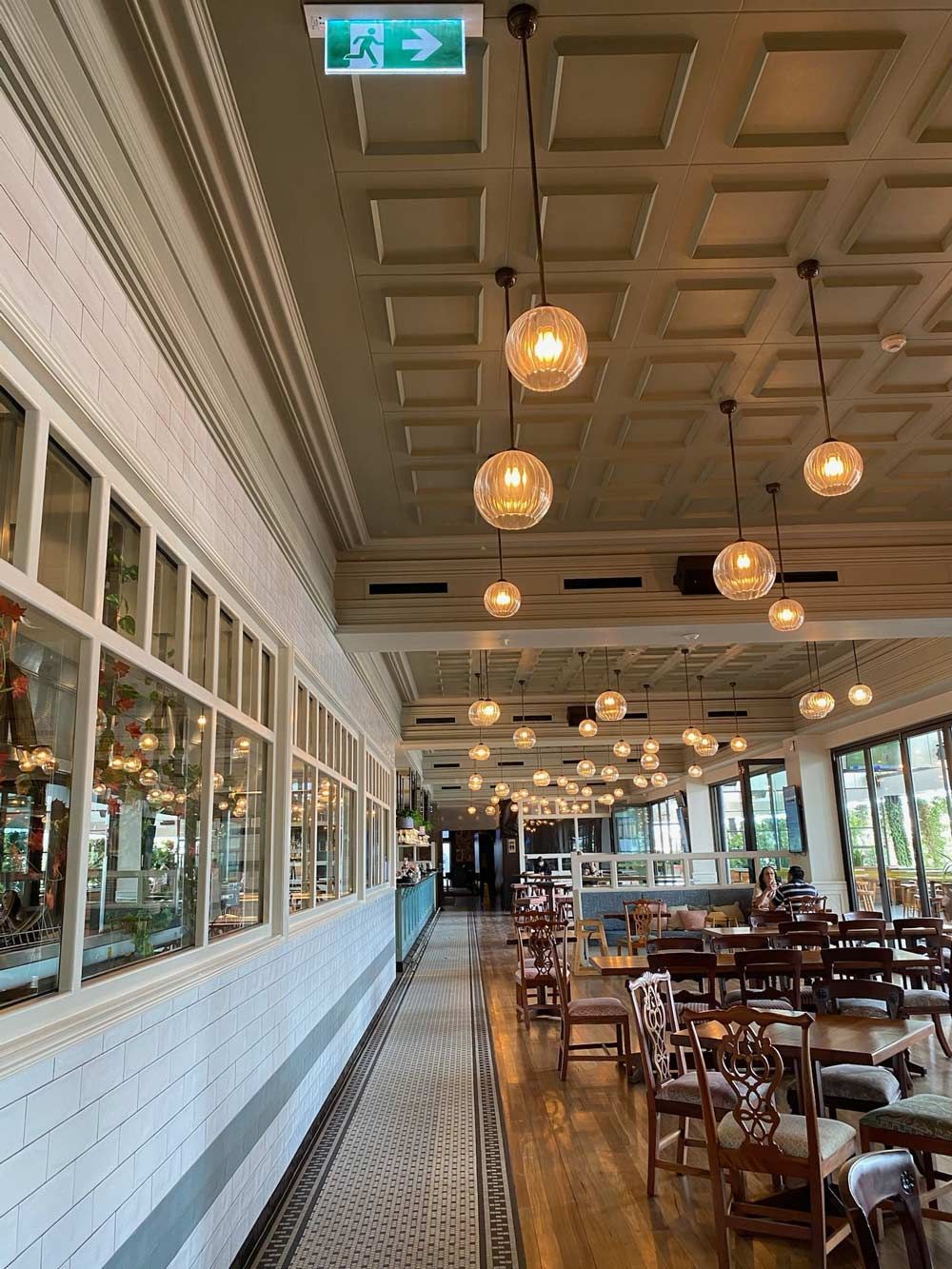 A long hallway in a restaurant with tables and chairs.