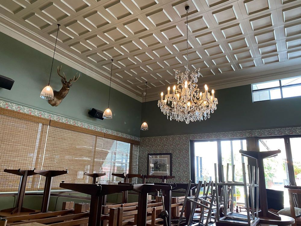 A room with tables and chairs and a chandelier hanging from the ceiling.