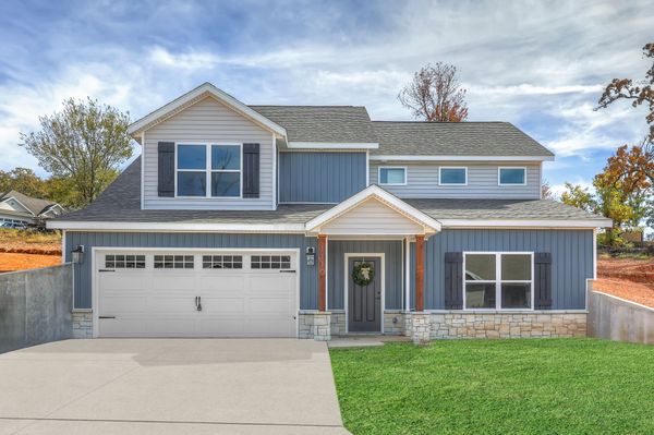 Two-story blue-gray suburban house with white trim, front garage, and a green lawn
