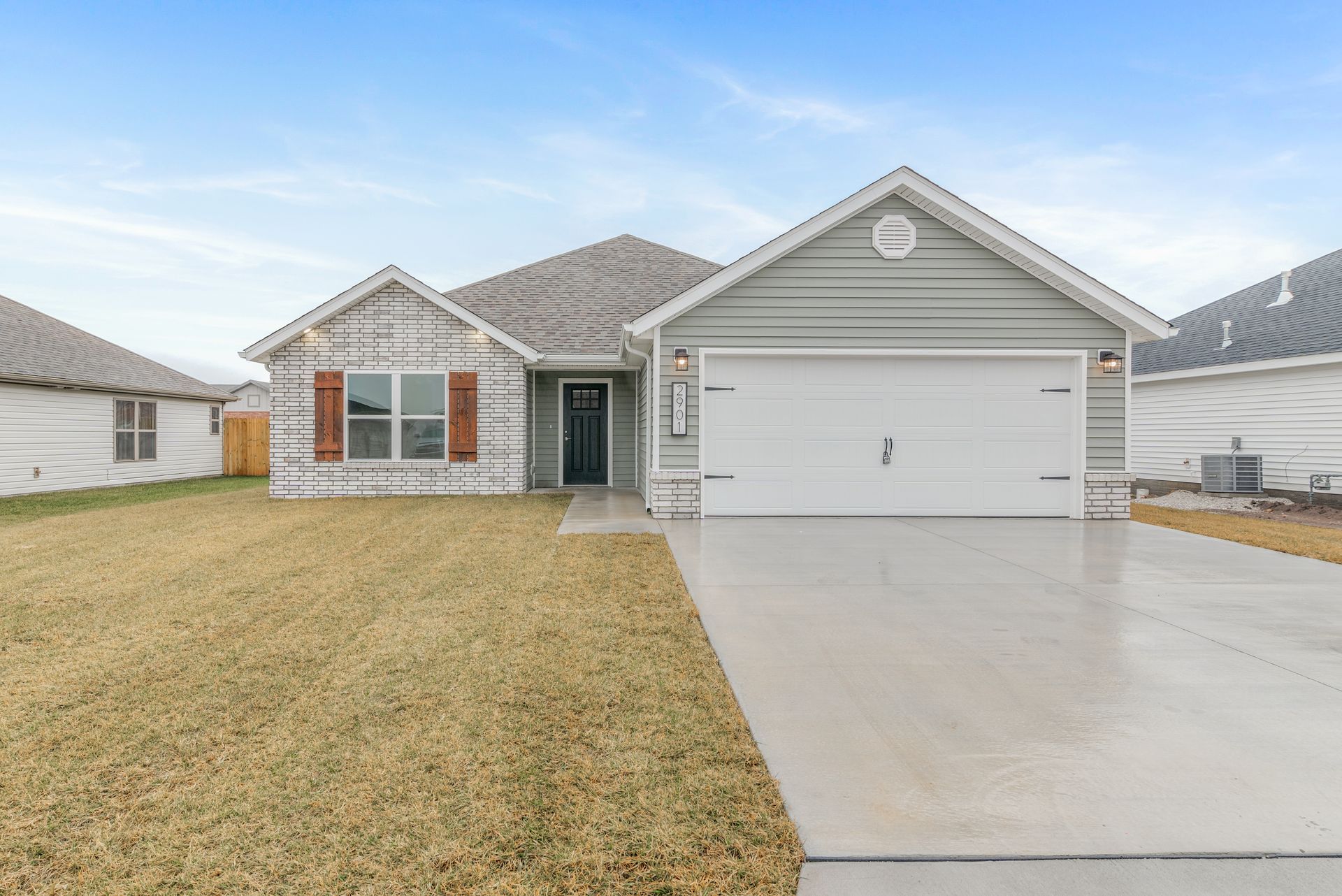 Single-story brick house with a two-car garage and concrete driveway in a suburban neighborhood