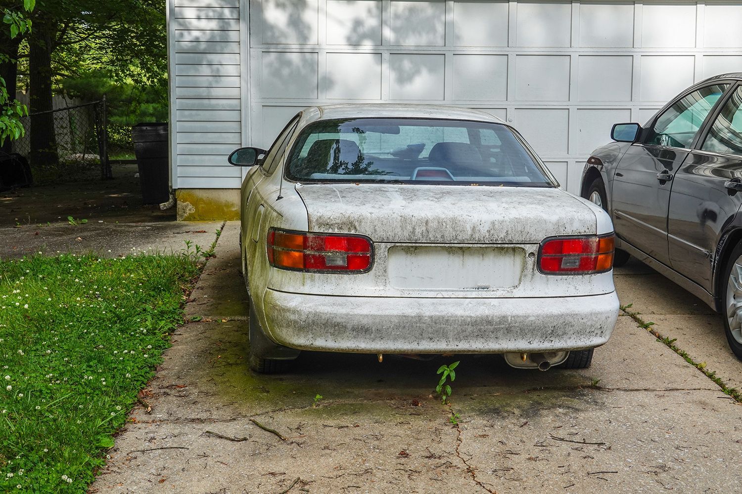 A junk car in front of a porch.