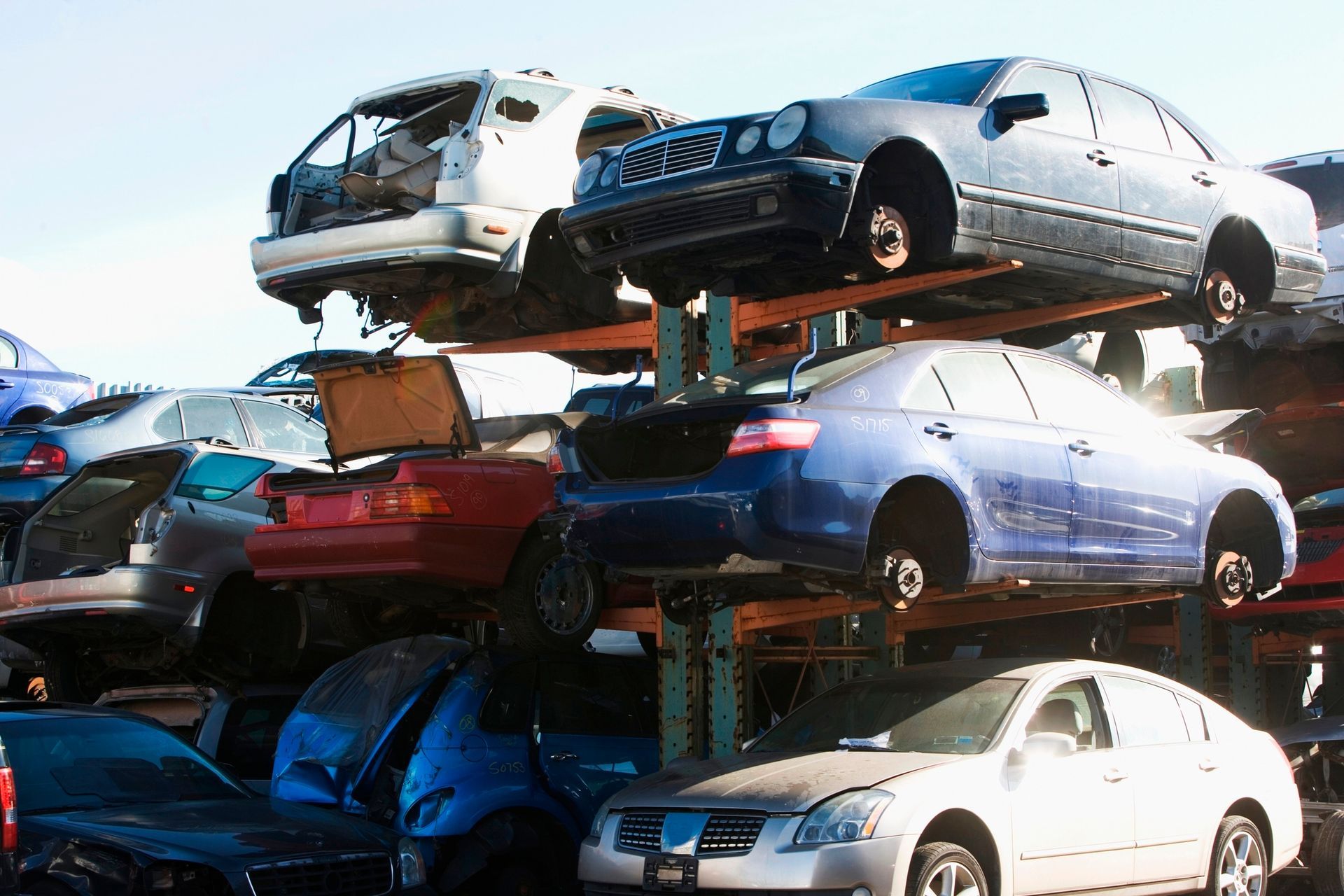 A row of old cars lined up in a junkyard awaiting recycling.