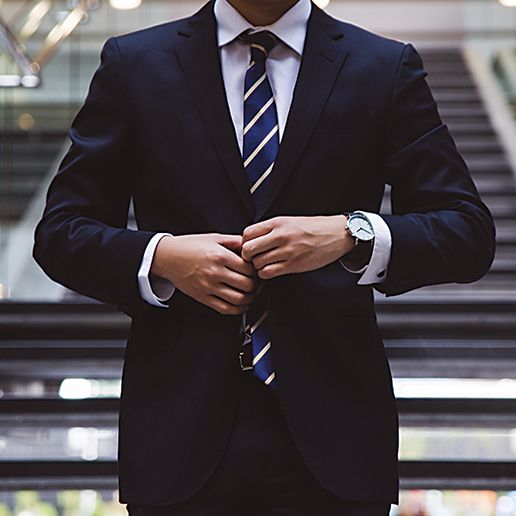 A well-dressed business executive buttons his suit coat.