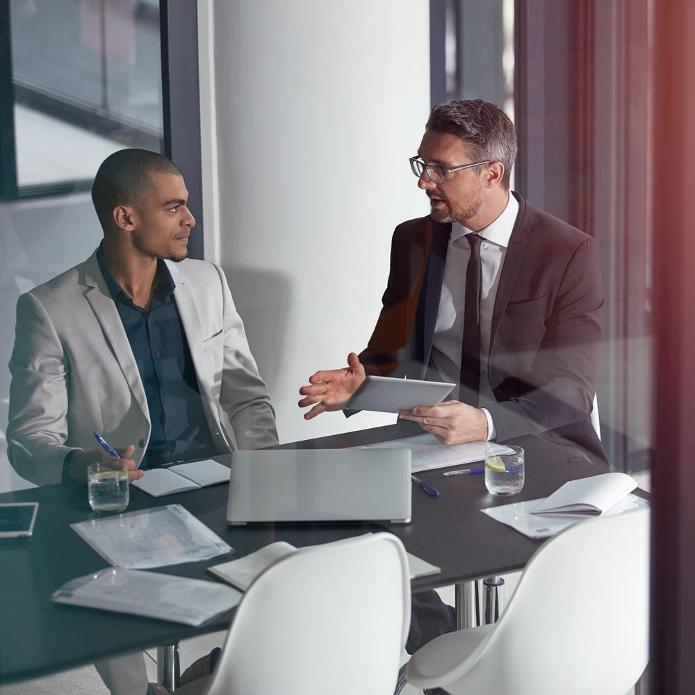 two men are sitting at a table talking to each other