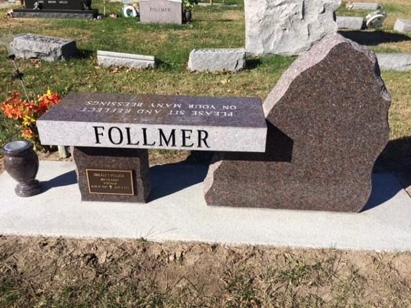 A granite memorial bench in a cemetery inscribed 