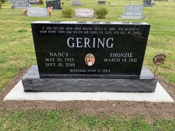 A black upright granite headstone for the Gering family, engraved with names, dates, and a biblical verse in a cemetery.