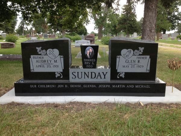 Black double headstone for Audrey and Glen Sunday in a cemetery, with the names of their six children engraved below.