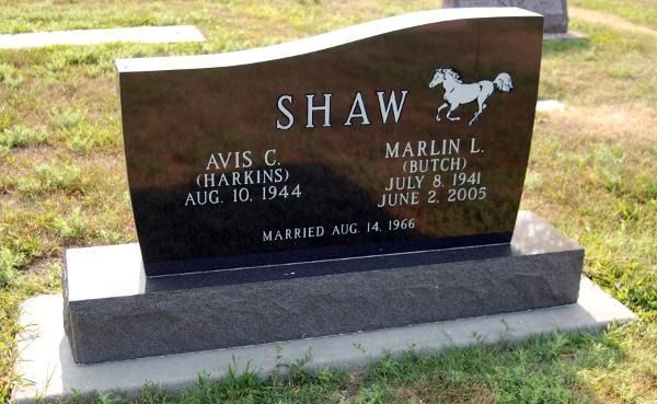 Black granite headstone for Avis and Marlin Shaw, featuring a horse engraving and marriage date on a base in a cemetery.