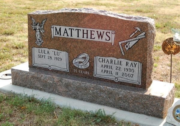 A reddish-brown granite headstone for Lula and Charlie Ray Matthews, featuring engraved tools and an angel.