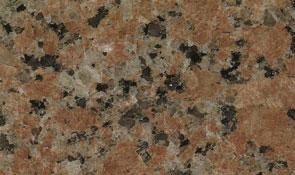 A close-up view of polished granite stone with a speckled pattern in shades of reddish-brown, tan, gray, and black.