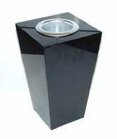 A sleek, black, tapered square trash receptacle with a central circular metal opening on a white background.