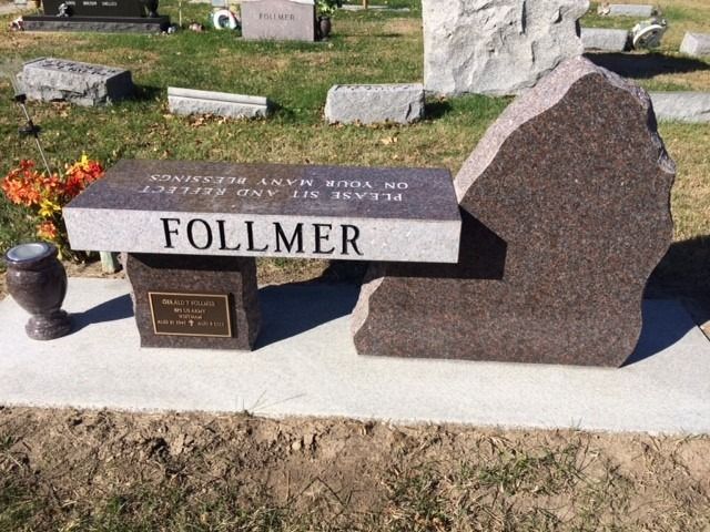 A brown granite memorial bench with the name FOLLMER inscribed, set in a cemetery.