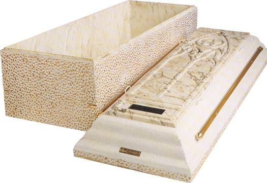 An open, textured beige casket with a matching lid featuring a raised, decorative floral carving and a gold side handle.