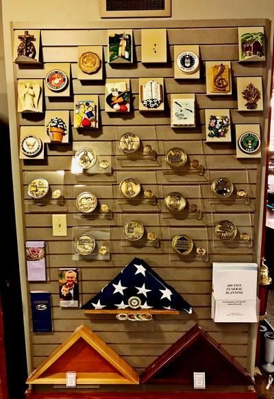 A display board featuring various military medals, plaques, and a folded U.S. flag with two empty flag cases below.