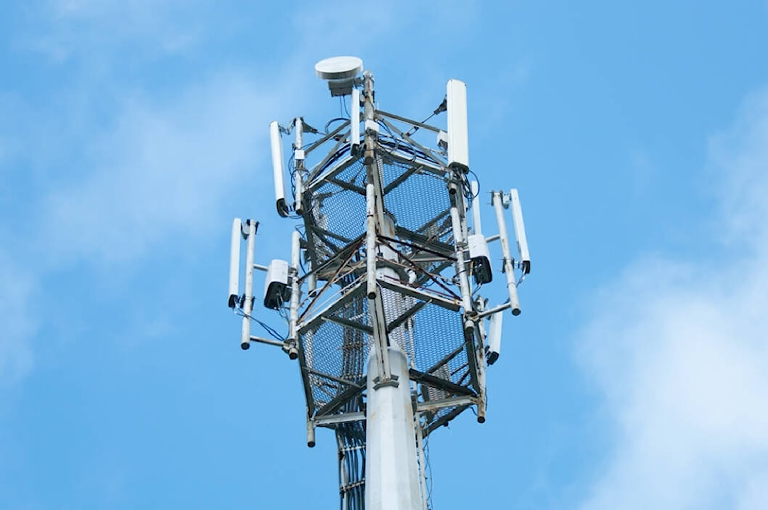 A cell phone tower with antennas against a blue sky.
